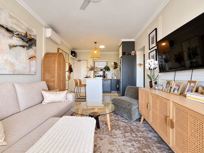 A well-presented open-plan living and kitchen area featuring modern cabinetry, a central island, split-system air conditioning, and elegant wall paneling details.