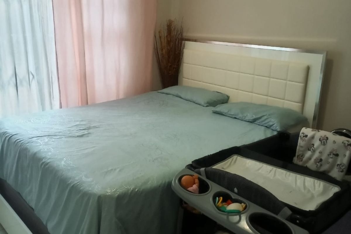 A bedroom featuring a sliding door with a security gate, providing access to the exterior.
