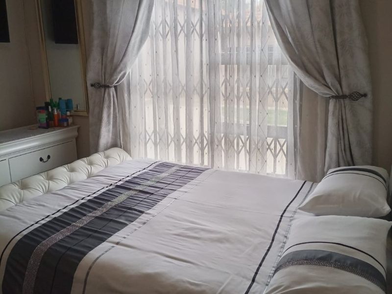 A bedroom featuring a window with a fitted security gate and curtain rod.