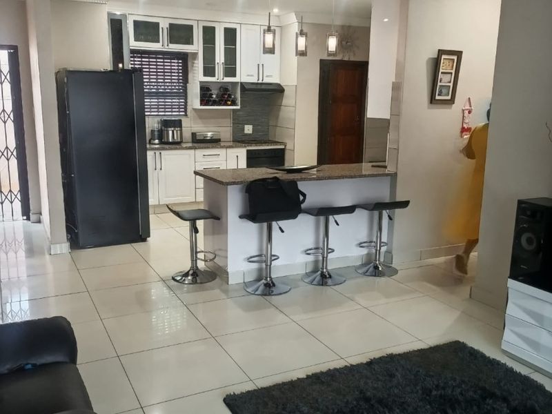 Open-plan living area featuring a modern kitchen with granite countertops, breakfast bar, and tiled flooring throughout.