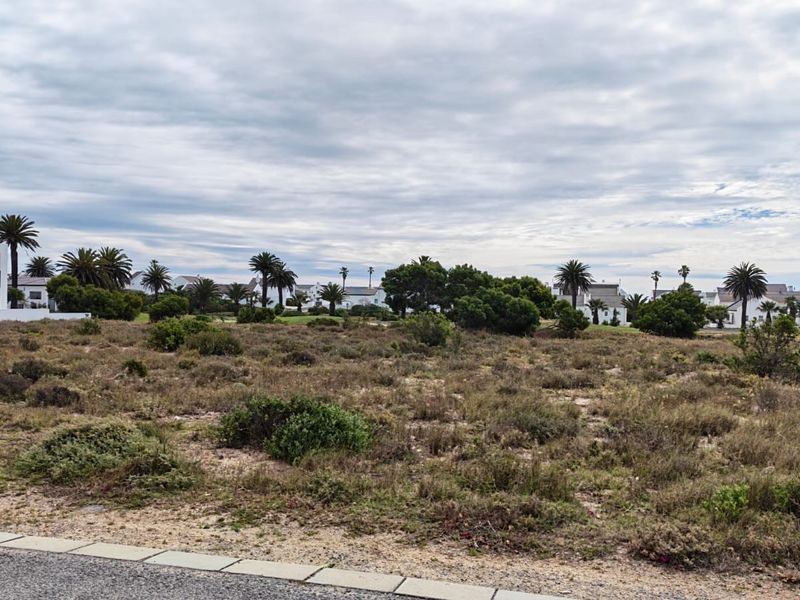 A vacant residential plot featuring native vegetation, situated in a developed estate with surrounding homes and established landscaping.