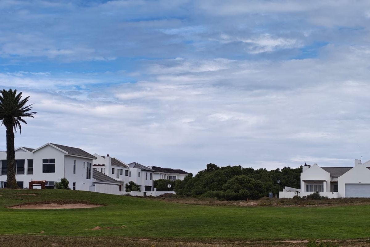 A view of residential properties overlooking a well-maintained green lawn and mature landscaping in a quiet estate setting.