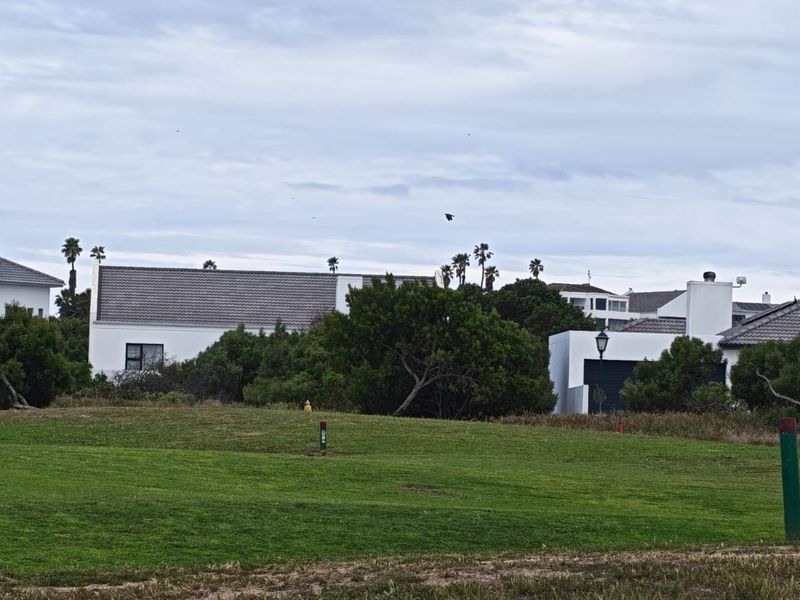 A view of residential properties situated behind a well-maintained green lawn area, showcasing the surrounding neighborhood landscape.