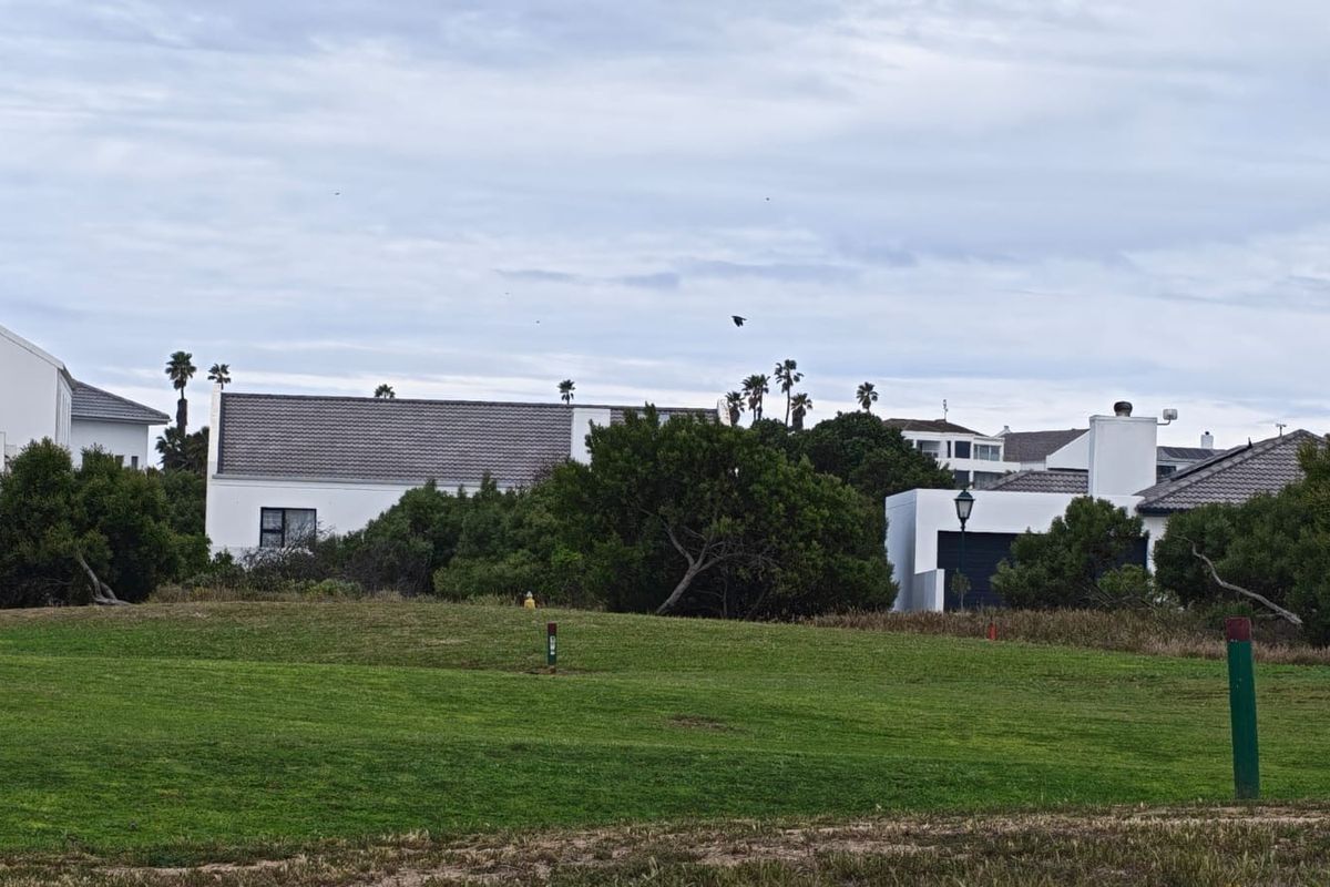 A view of residential properties situated behind a well-maintained green lawn area, showcasing the surrounding neighborhood landscape.