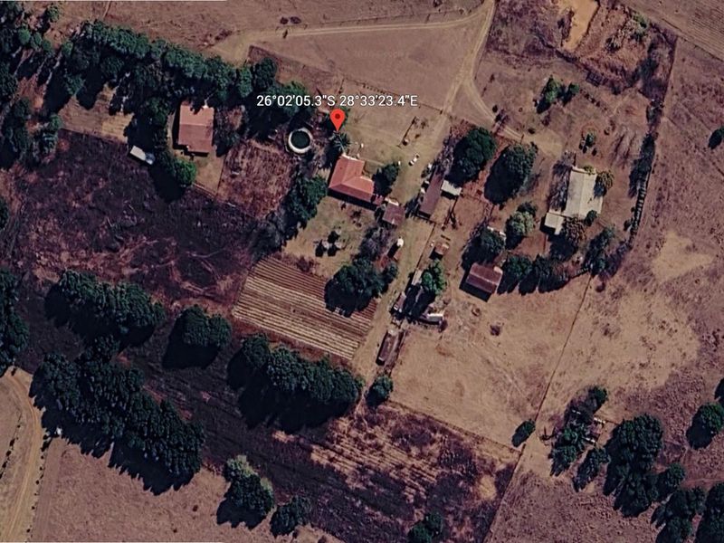 Aerial view of a farm property featuring multiple outbuildings, a swimming pool, and cultivated land areas.