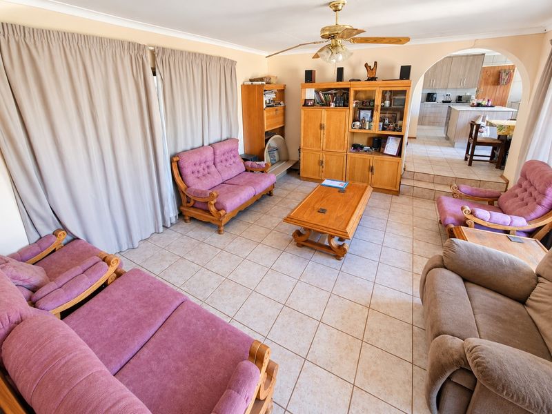 Open plan living area featuring tiled flooring, a ceiling fan, and an arched transition leading into a functional kitchen space.