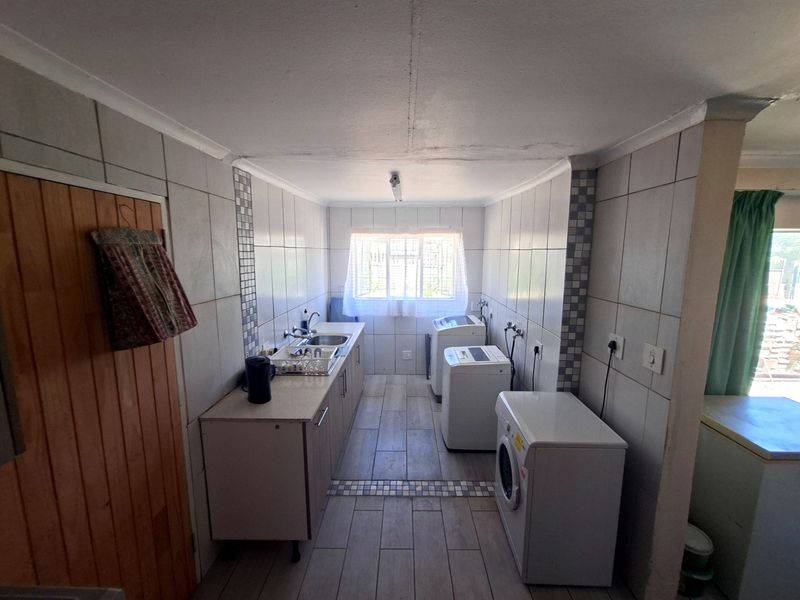 Functional laundry room featuring tiled walls and flooring, built-in cabinetry, and dedicated plumbing connections for appliances.
