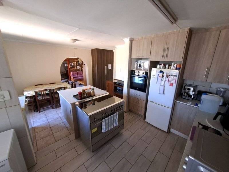 Open-plan kitchen featuring a central island, built-in cabinetry, and a freestanding stove, seamlessly connecting to the adjacent dining area through a classic archway.