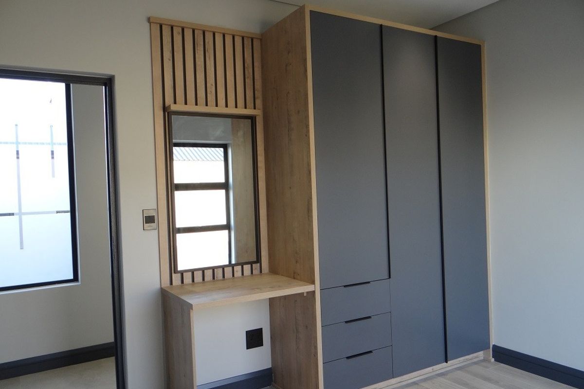 Modern bedroom featuring high-quality built-in cupboards with an integrated vanity and stylish slatted wood detailing.