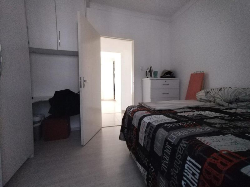 A functional bedroom featuring built-in cupboards and laminate flooring, providing a practical living space with direct access to the hallway.