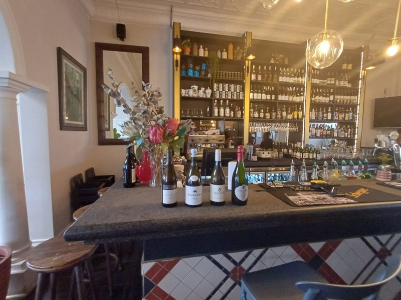 A well-appointed bar area featuring a tiled counter, extensive built-in shelving for glassware and spirits, and decorative ceiling cornicing.