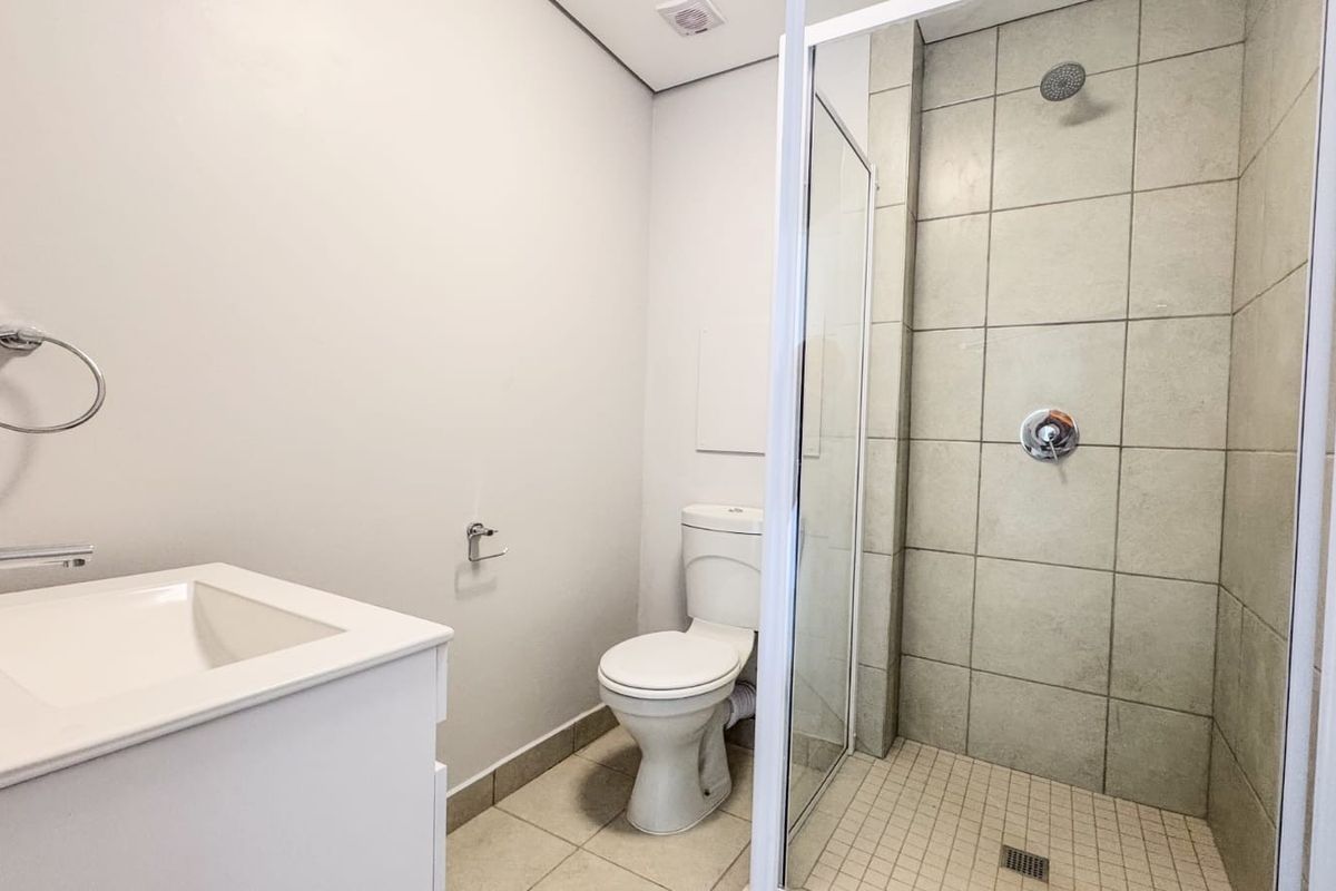 A clean and modern bathroom featuring a vanity with basin, a toilet, and a glass-enclosed shower with tiled finishes.