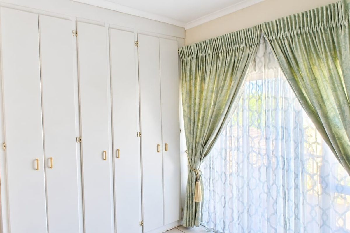 A bright bedroom featuring extensive built-in cupboards and a sliding door leading to the exterior, providing ample storage and natural light.