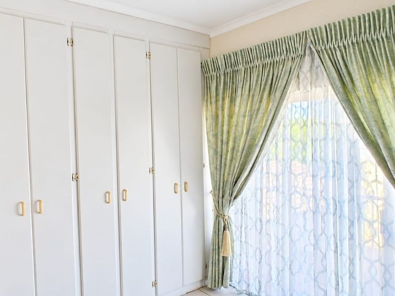 A bright bedroom featuring extensive built-in cupboards and a sliding door leading to the exterior, providing ample storage and natural light.