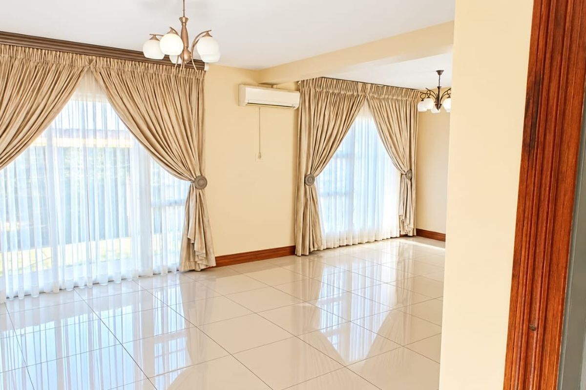 Spacious, light-filled living area featuring polished tiled flooring, split-system air conditioning, and large windows dressed with elegant curtains.