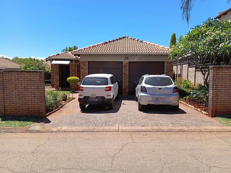 Front view of a townhouse featuring a double garage, brick paved driveway, and facebrick exterior finish.