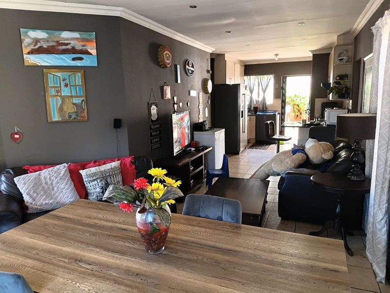Open-plan living and dining area flowing into a functional kitchen space with tiled flooring and neutral wall finishes.