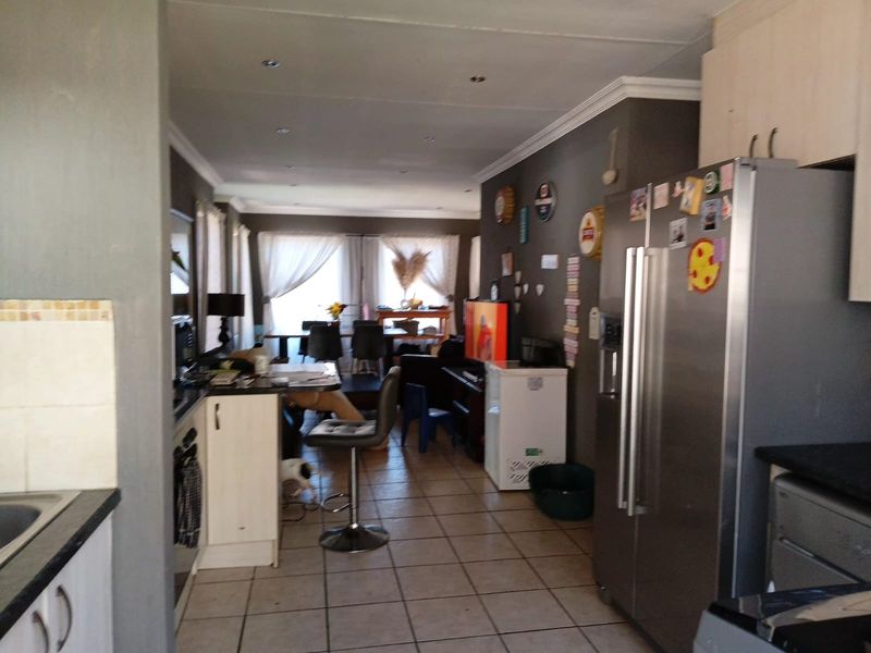 An open-plan living and kitchen area featuring tiled flooring, recessed lighting, and functional kitchen cabinetry with a breakfast counter.