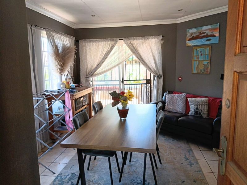 An open-plan living and dining area featuring tiled flooring, recessed lighting, and a sliding glass door with security gate leading to the exterior.