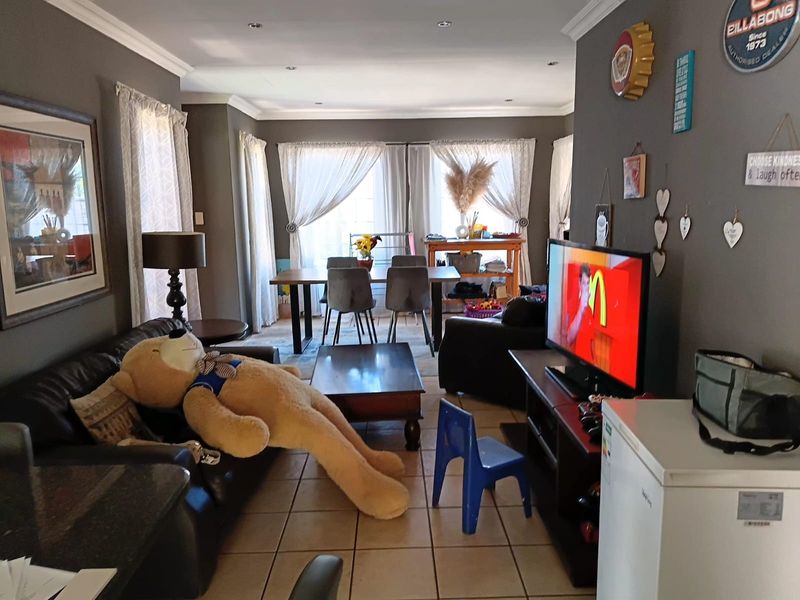 Open-plan living and dining area featuring tiled flooring, recessed downlighting, and decorative cornicing, providing a versatile space for family living.