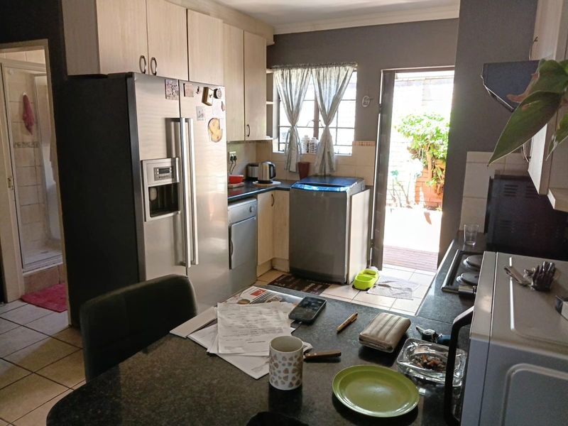 A functional kitchen featuring built-in cabinetry, granite countertops, and a hob, with direct access to an outdoor patio area.