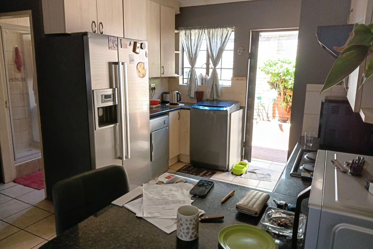 A functional kitchen featuring built-in cabinetry, granite countertops, and a hob, with direct access to an outdoor patio area.