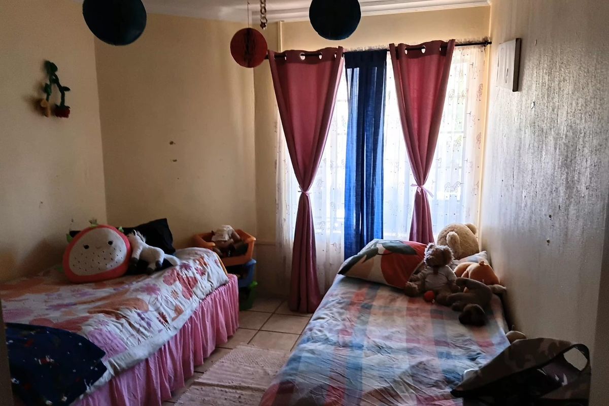 A bedroom featuring tiled flooring and coving, currently showing signs of wear on the wall surfaces.