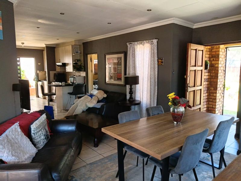 Open-plan living, dining, and kitchen area featuring tiled flooring, recessed lighting, and a functional kitchen layout with built-in cabinetry.