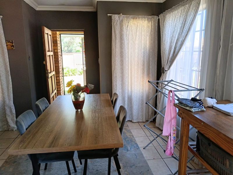 A dining room featuring tiled flooring, neutral wall paint, and direct access to the exterior through a timber door.