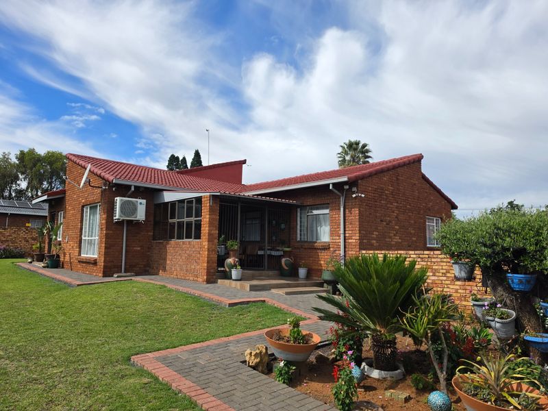A well-maintained face brick house featuring a tiled roof, paved pathways, and a landscaped garden area.