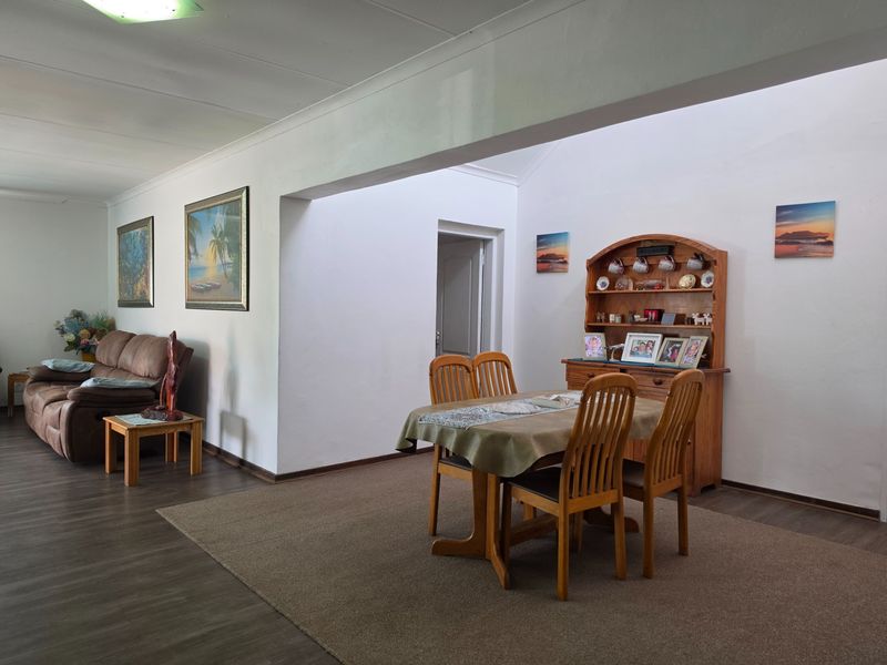 Spacious open-plan living and dining area featuring neutral walls, laminate flooring, and a coved ceiling, offering a versatile layout for family living.