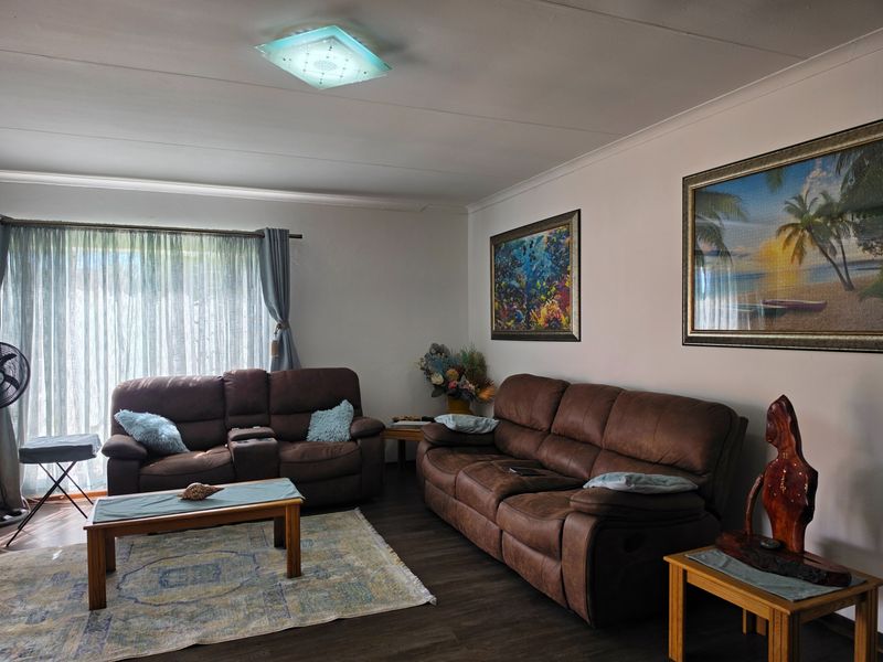 A comfortable living room featuring laminate flooring, a ceiling light fixture, and a large sliding glass door providing natural light.