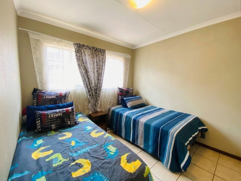 A functional bedroom featuring tiled flooring and neutral wall finishes, providing a comfortable space with natural light from the window.