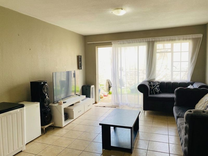 A living room featuring tiled flooring and a sliding glass door providing access to the outdoor area, offering a functional and well-lit space.