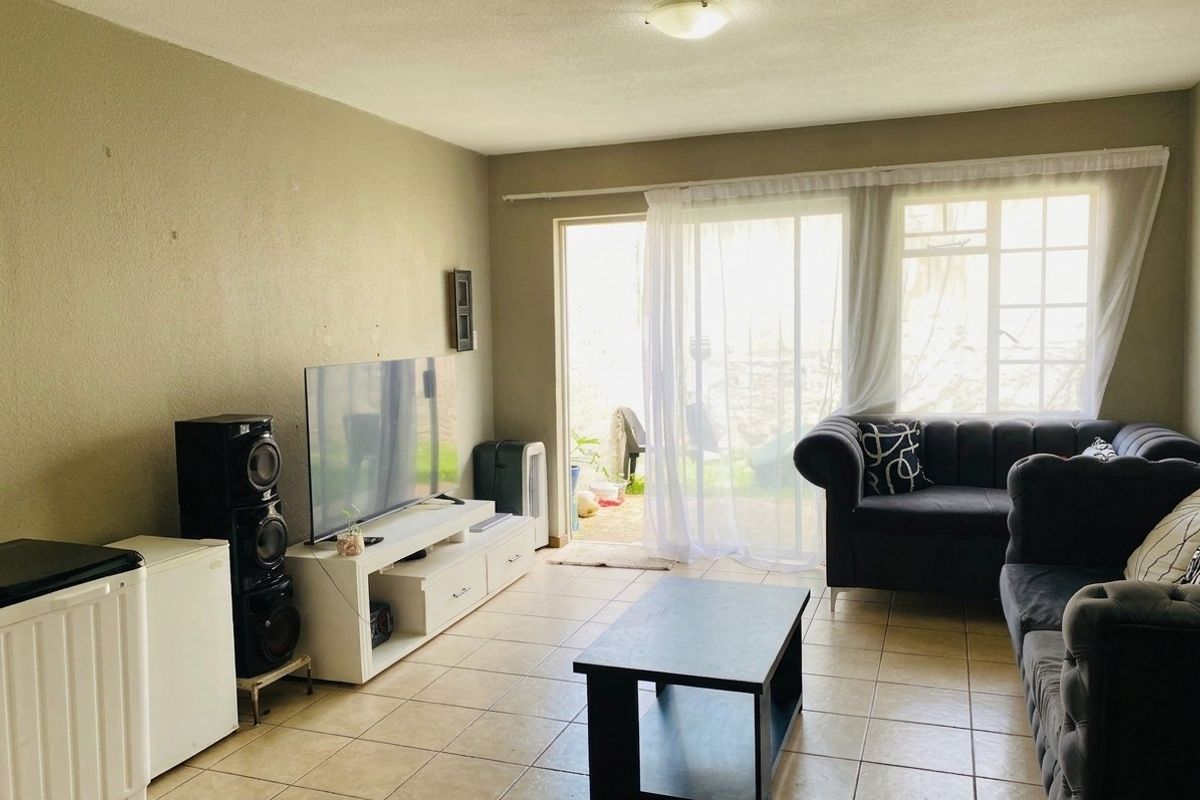 A living room featuring tiled flooring and a sliding glass door providing access to the outdoor area, offering a functional and well-lit space.
