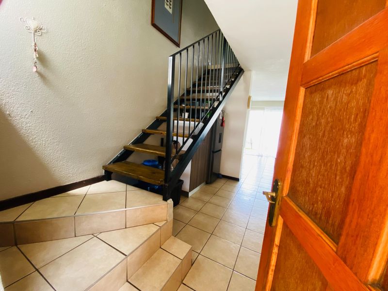Entrance area featuring a tiled floor and an open-tread staircase with a metal balustrade, leading towards the main living space.