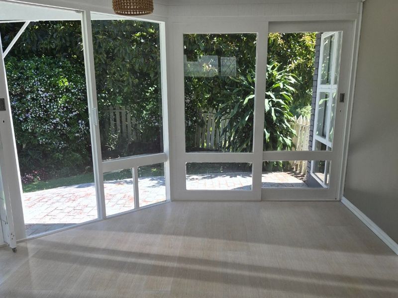 Bright and airy living space featuring large glass sliding doors that open to the garden, complemented by modern timber-look flooring.