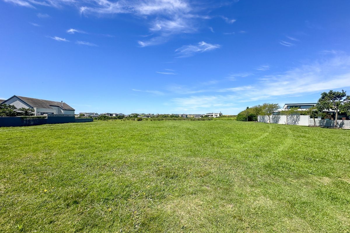 A spacious, level residential vacant land plot featuring well-maintained grass and surrounding boundary walls in a quiet neighborhood setting.