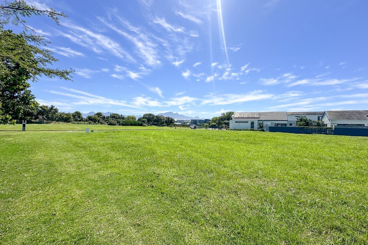 A spacious, well-maintained vacant residential plot featuring a level lawn with clear views of the surrounding neighbourhood and distant mountains.