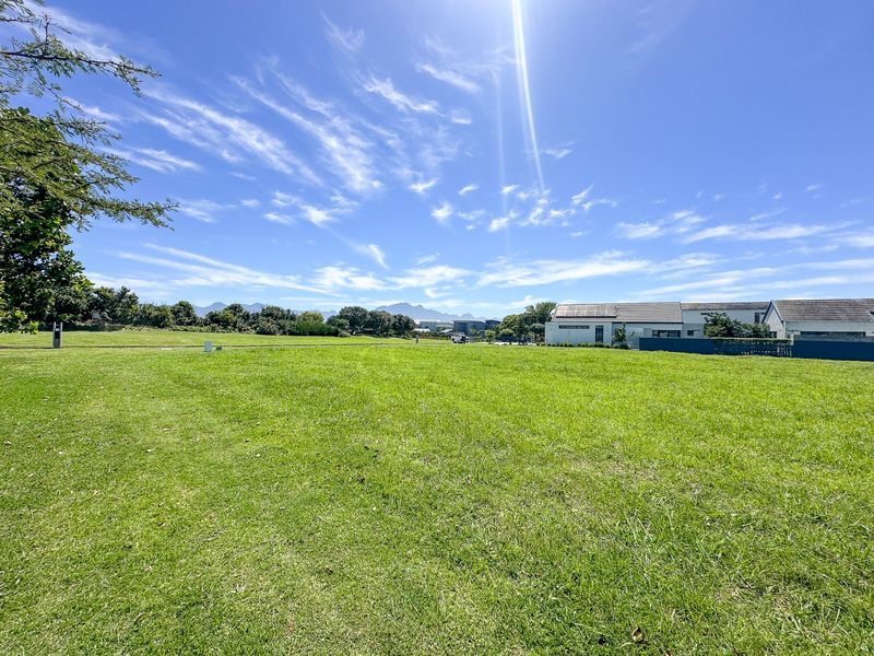 A spacious, well-maintained vacant residential plot featuring a level lawn with clear views of the surrounding neighbourhood and distant mountains.