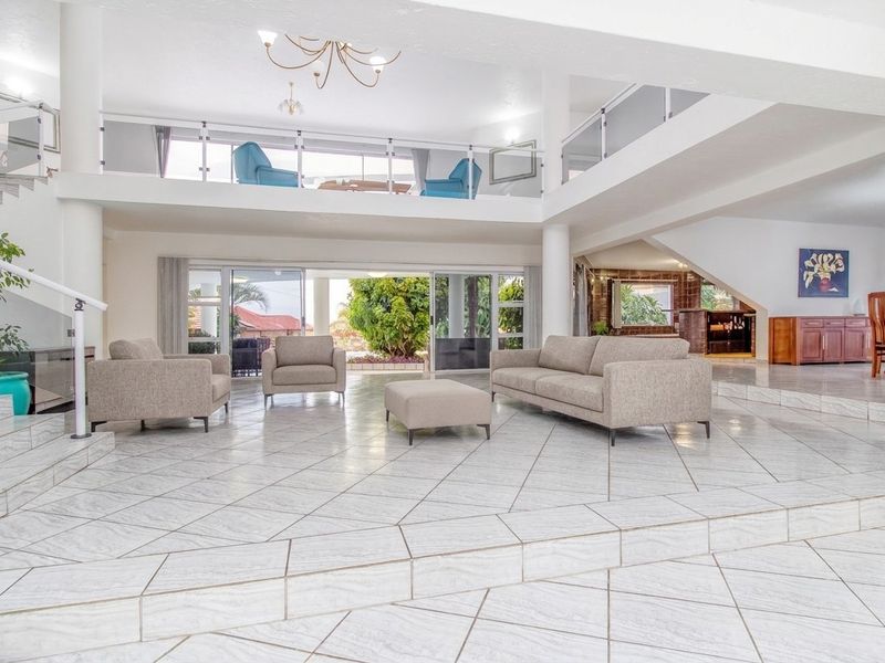 Spacious open-plan living area featuring a mezzanine level, tiled flooring, and large sliding glass doors that provide seamless access to the outdoor space.