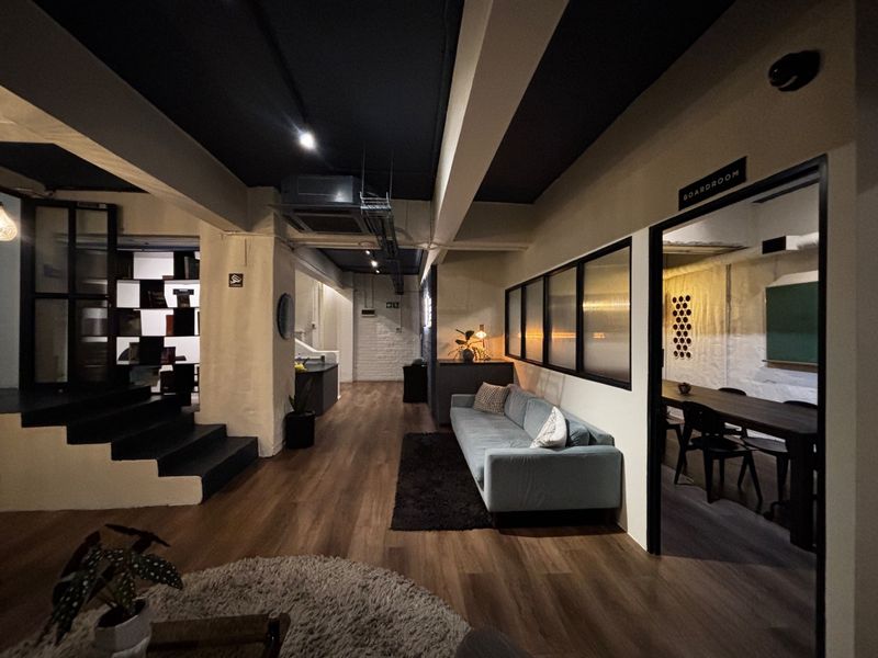 Modern open-plan office or apartment space featuring exposed industrial-style ceilings, timber flooring, and a dedicated boardroom with glass partitioning.