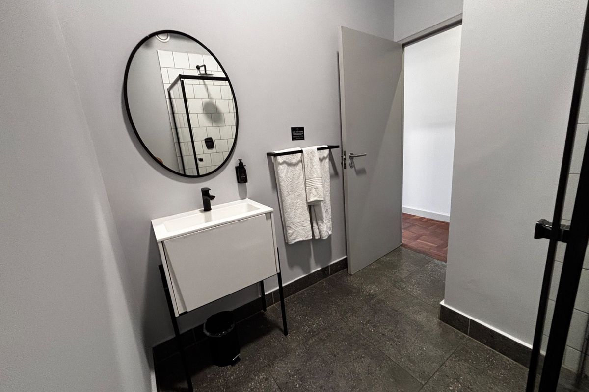Modern bathroom featuring a sleek vanity with basin, dark tiled flooring, and a glass-enclosed shower with subway tile detailing.
