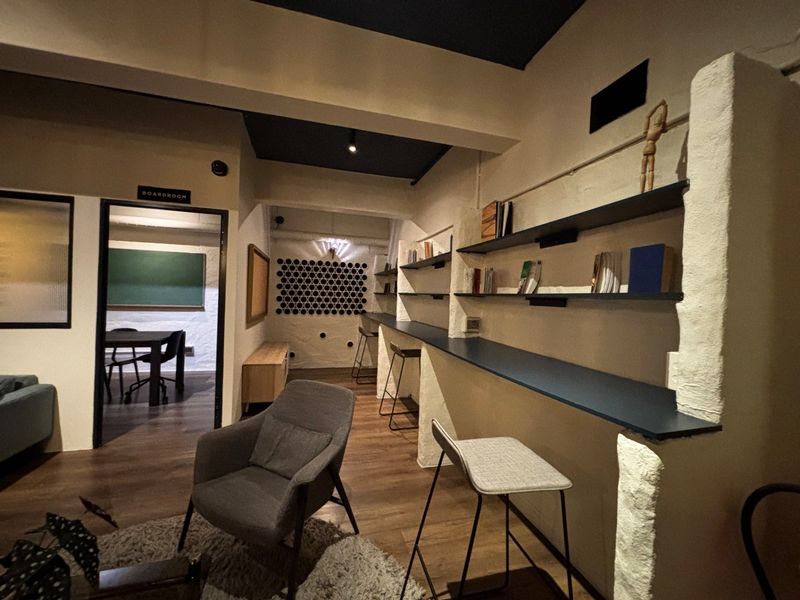 Open plan living and workspace area featuring built-in shelving, a long desk counter, and textured wall finishes with a modern industrial aesthetic.