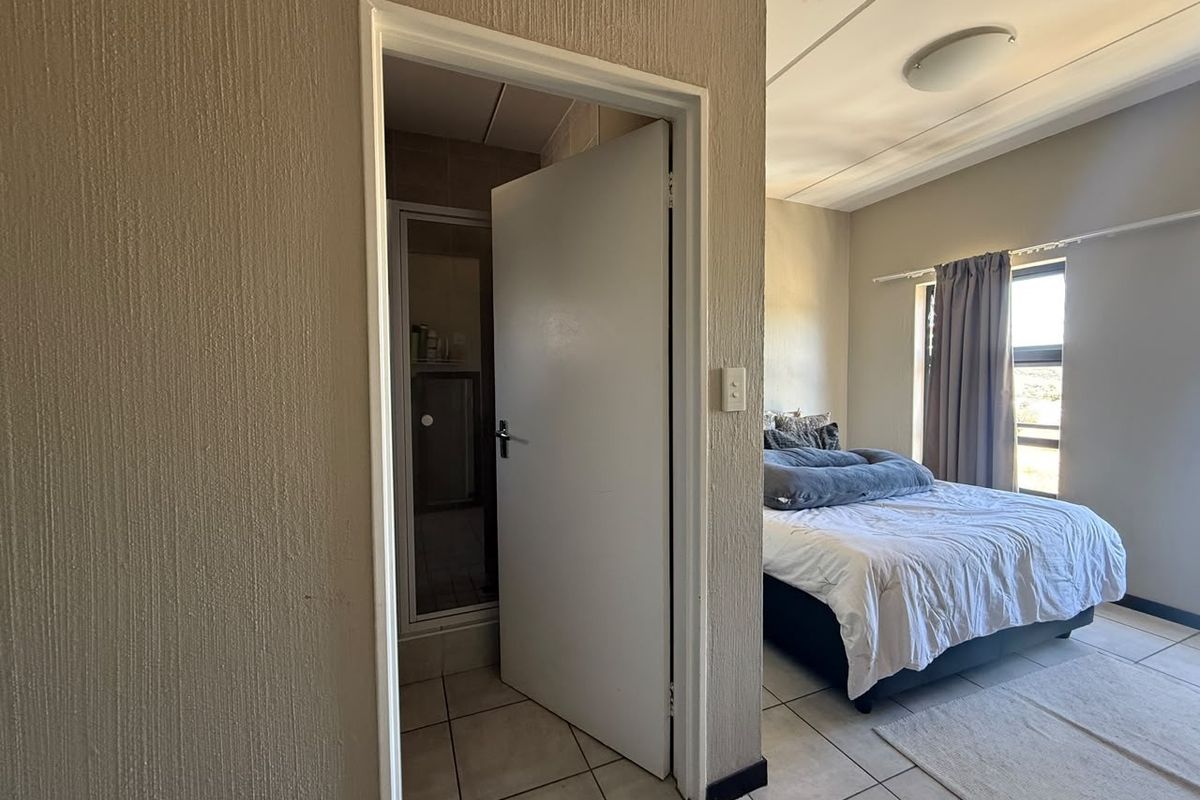A bedroom featuring tiled flooring and an attached en-suite bathroom with a shower enclosure.