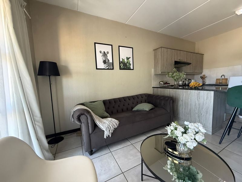 Open-plan living area featuring a compact kitchen with granite countertops, breakfast bar, and tiled flooring throughout.