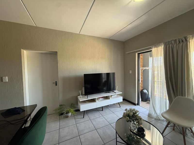 A living room featuring tiled flooring, textured walls, and a sliding glass door providing access to an outdoor area.