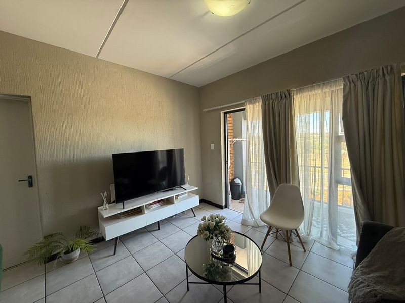 A living room featuring tiled flooring and a sliding glass door providing access to an outdoor balcony area.