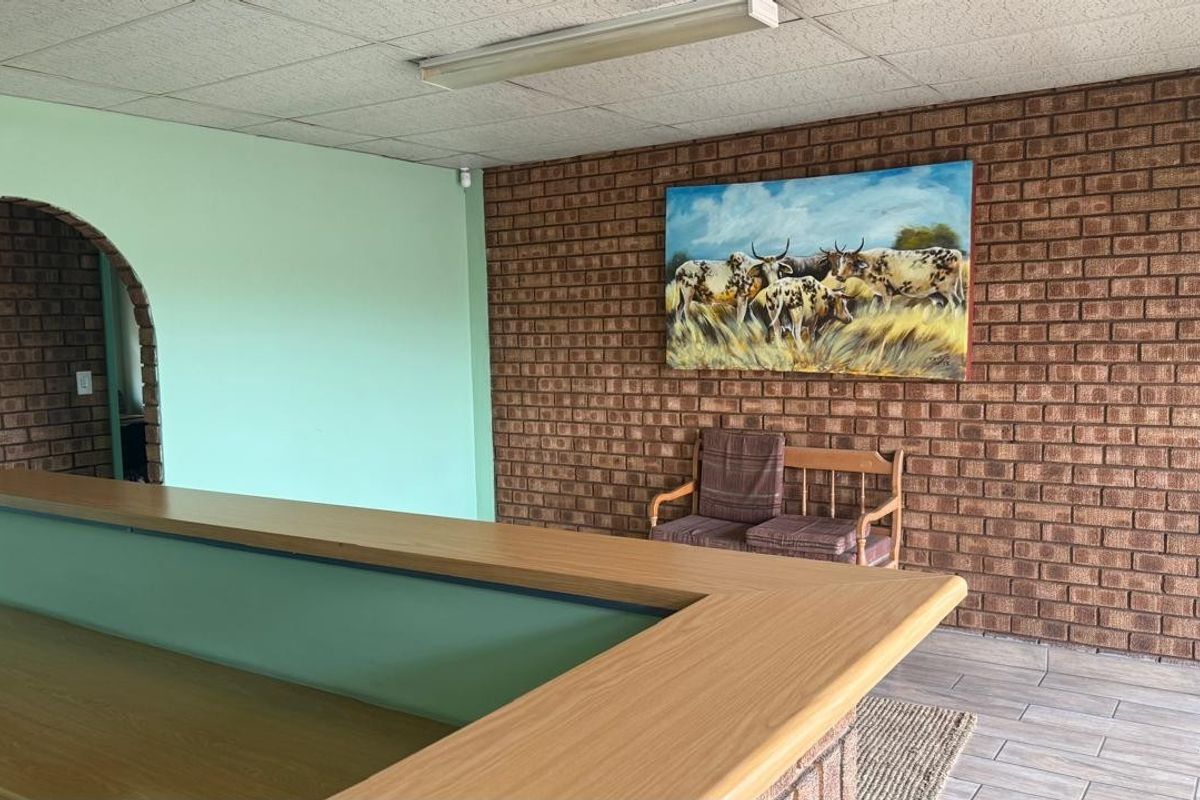 Interior space featuring exposed brick walls, tiled flooring, and a drop ceiling with integrated lighting, suitable for office or reception use.