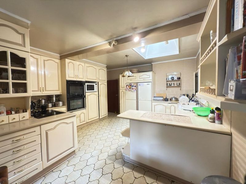 Spacious kitchen featuring traditional cabinetry, a double wall oven, built-in microwave, breakfast bar, and a skylight providing natural light.